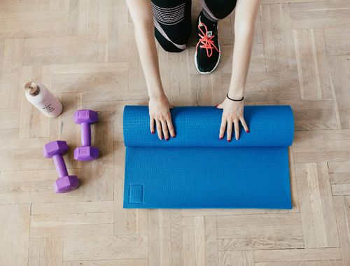 Close-up of yoga mat and water bottle on a wooden floor.